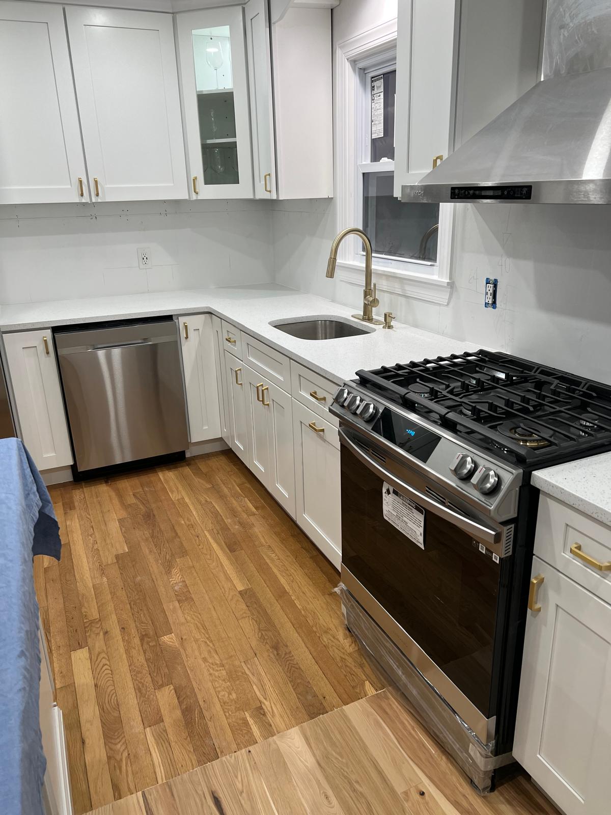 Updated white kitchen with stainless steel range and gold-tone fixtures