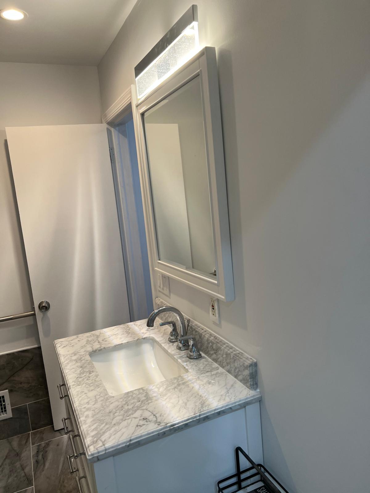 Updated bathroom vanity with stone-pattern counter and framed mirror