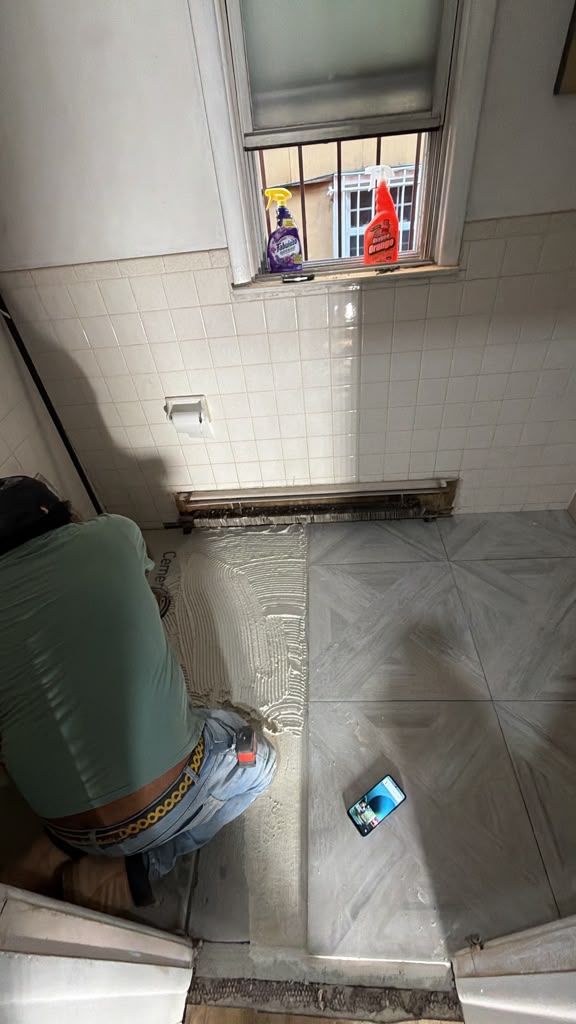 Worker setting large-format floor tile during a Clifton, New Jersey interior project